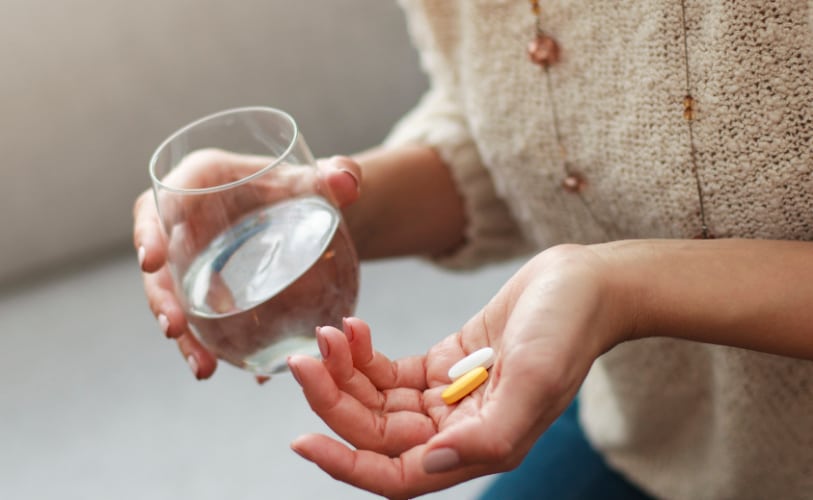 Person taking medication with a glass of water